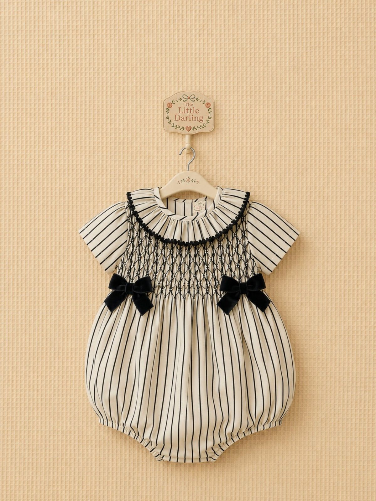 Striped smocked baby romper with black velvet bows.