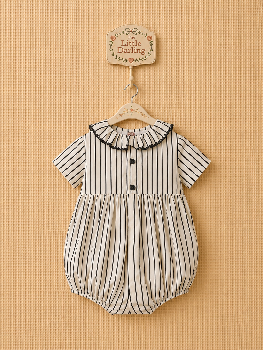 Striped smocked baby romper with black velvet bows.