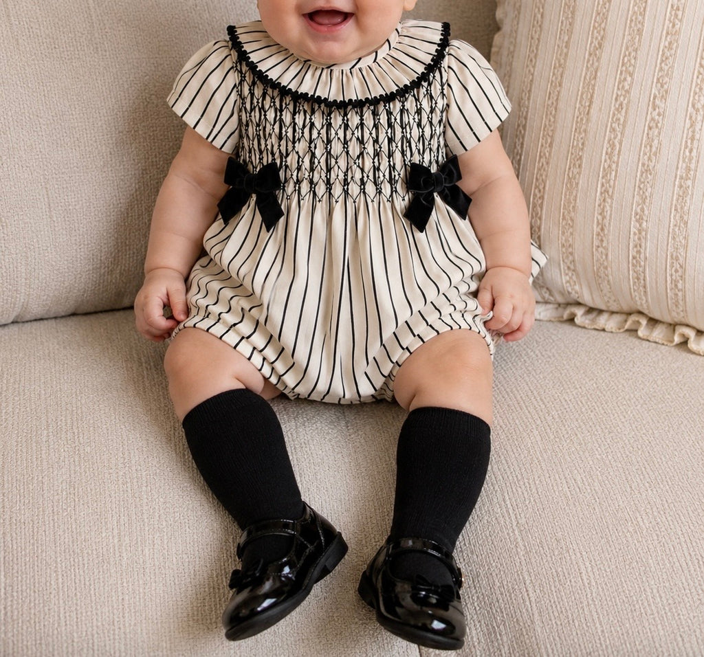 Striped smocked baby romper with black velvet bows.
