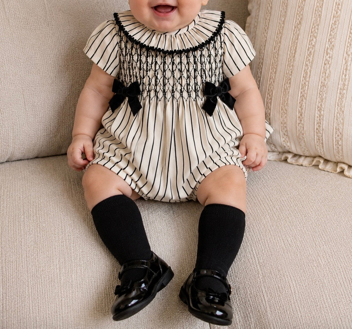 Striped smocked baby romper with black velvet bows.