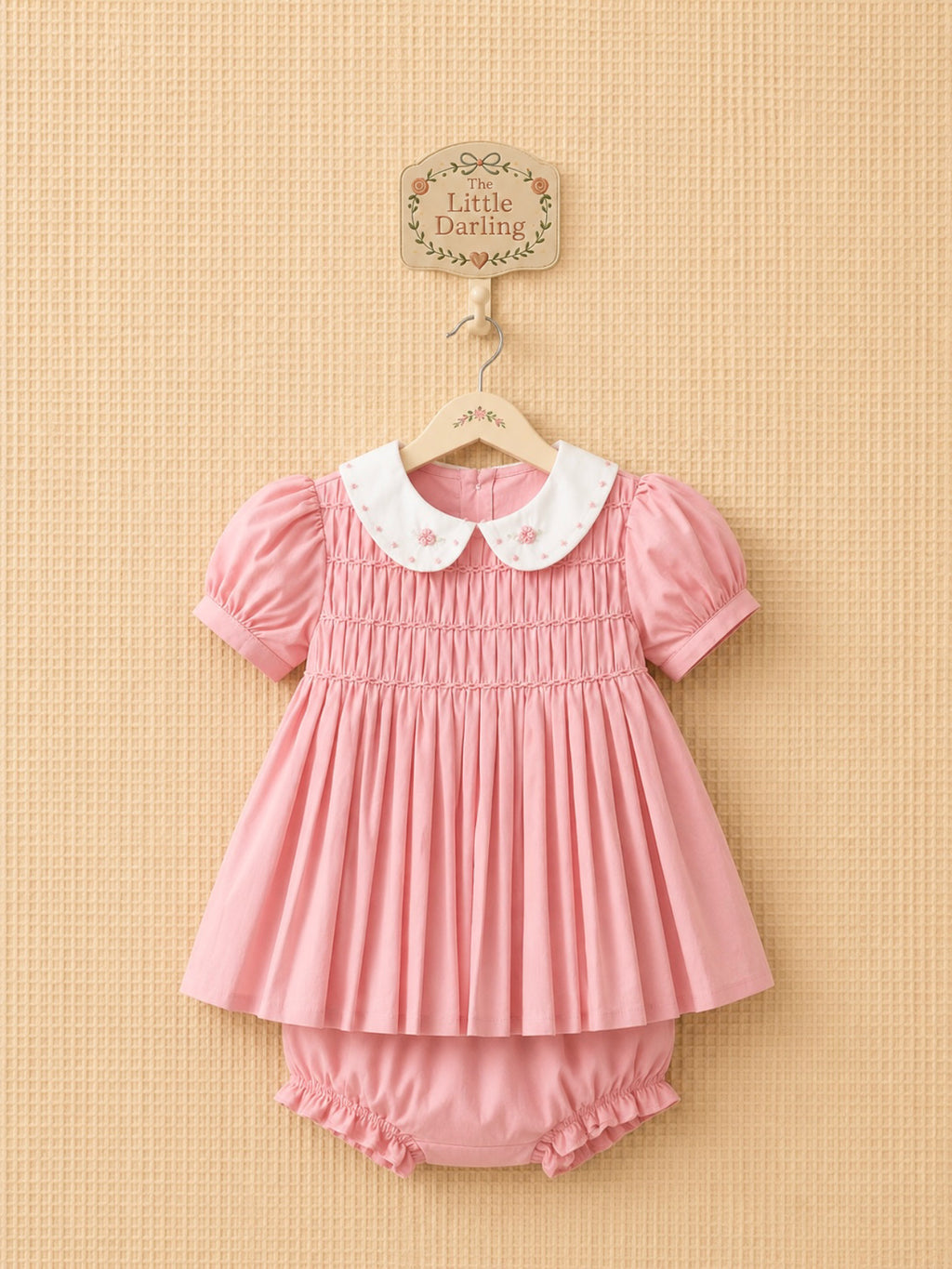 Pink smocked dress with an embroidered white collar, matching bloomers.