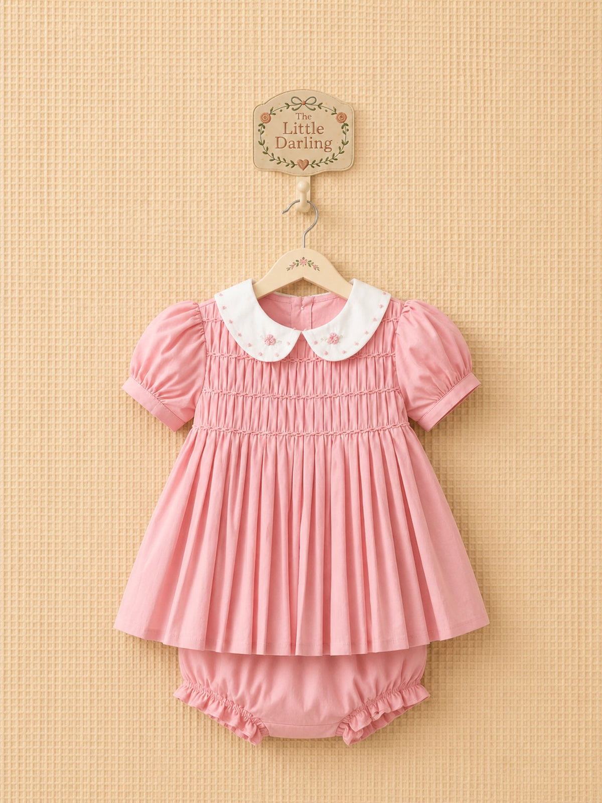 Pink smocked dress with an embroidered white collar, matching bloomers.